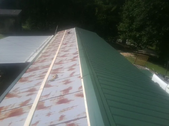 Old rusted panels beside newly installed green metal roofing — Wind Damage Roof Repair by Roofing Brothers in Floyd