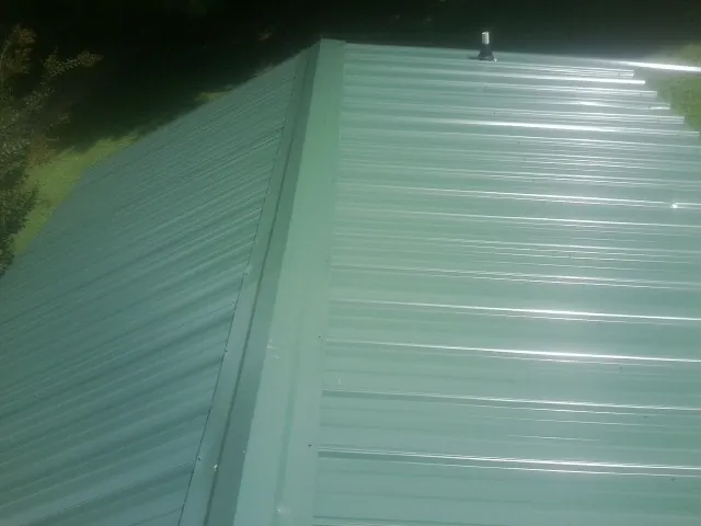 New green metal panels meeting at the ridge of a roof — Flat Roof Repair work by our crew in Floyd