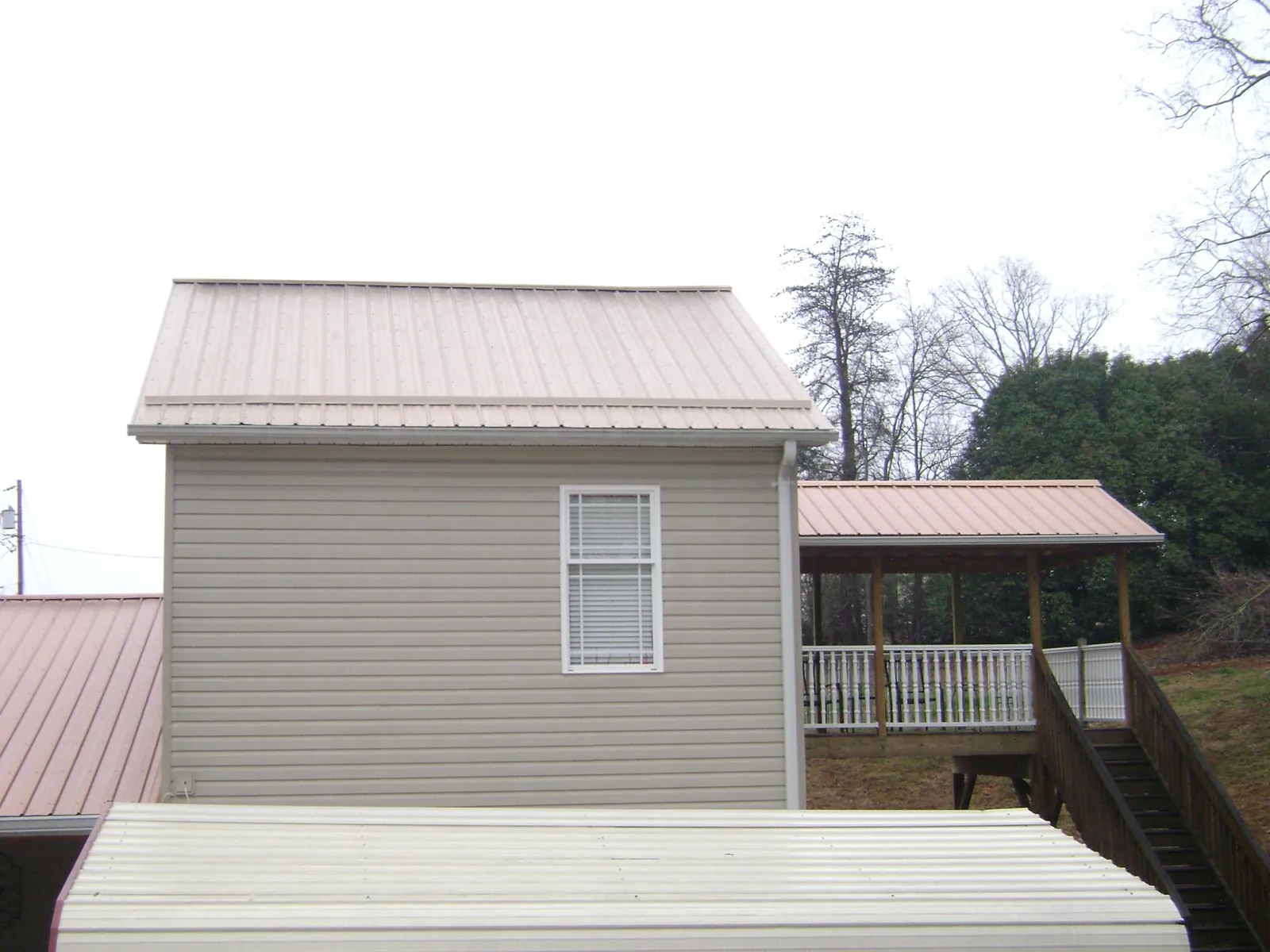 Tan metal roofs on a two story addition and attached porch, from a Roof Replacement job in Floyd